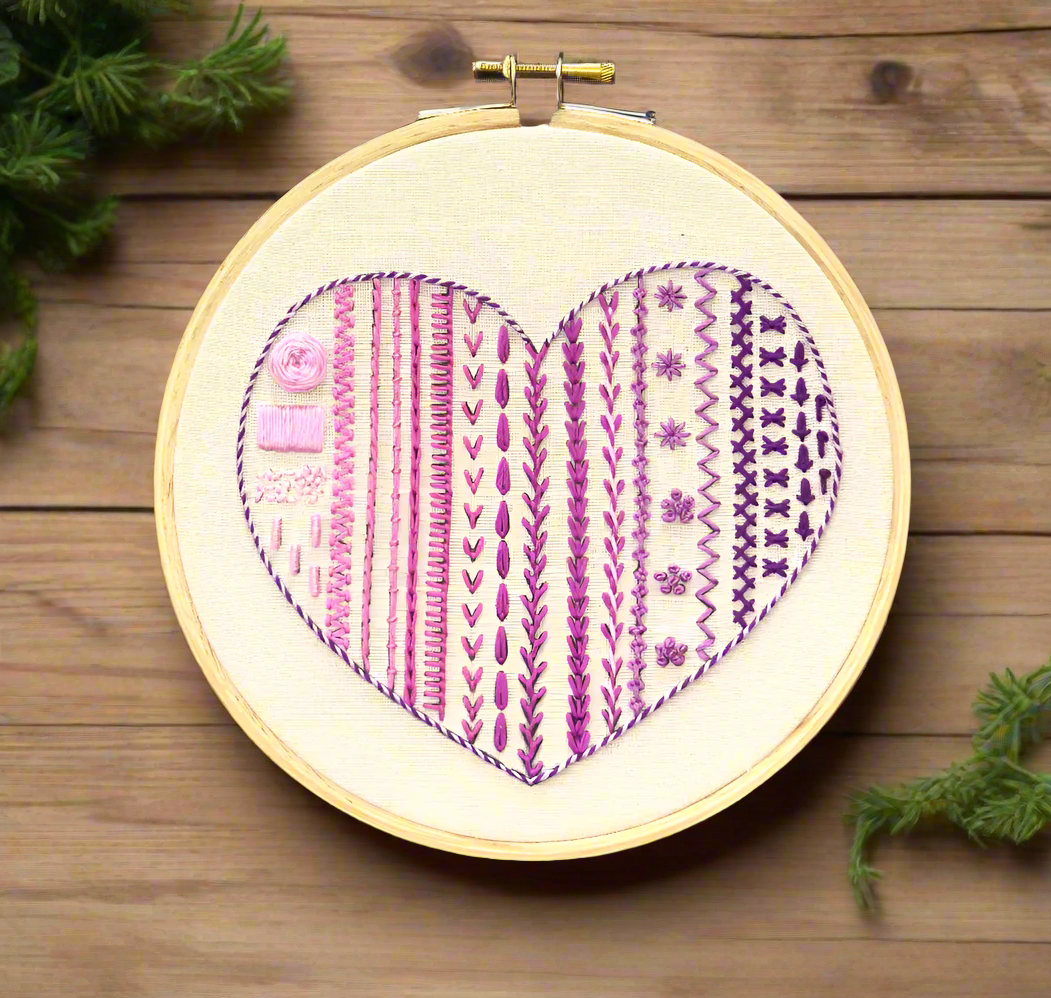Embroidery hoop art with heart shape design, multiple stitches. modern embroidery pattern in different shades of purple thread