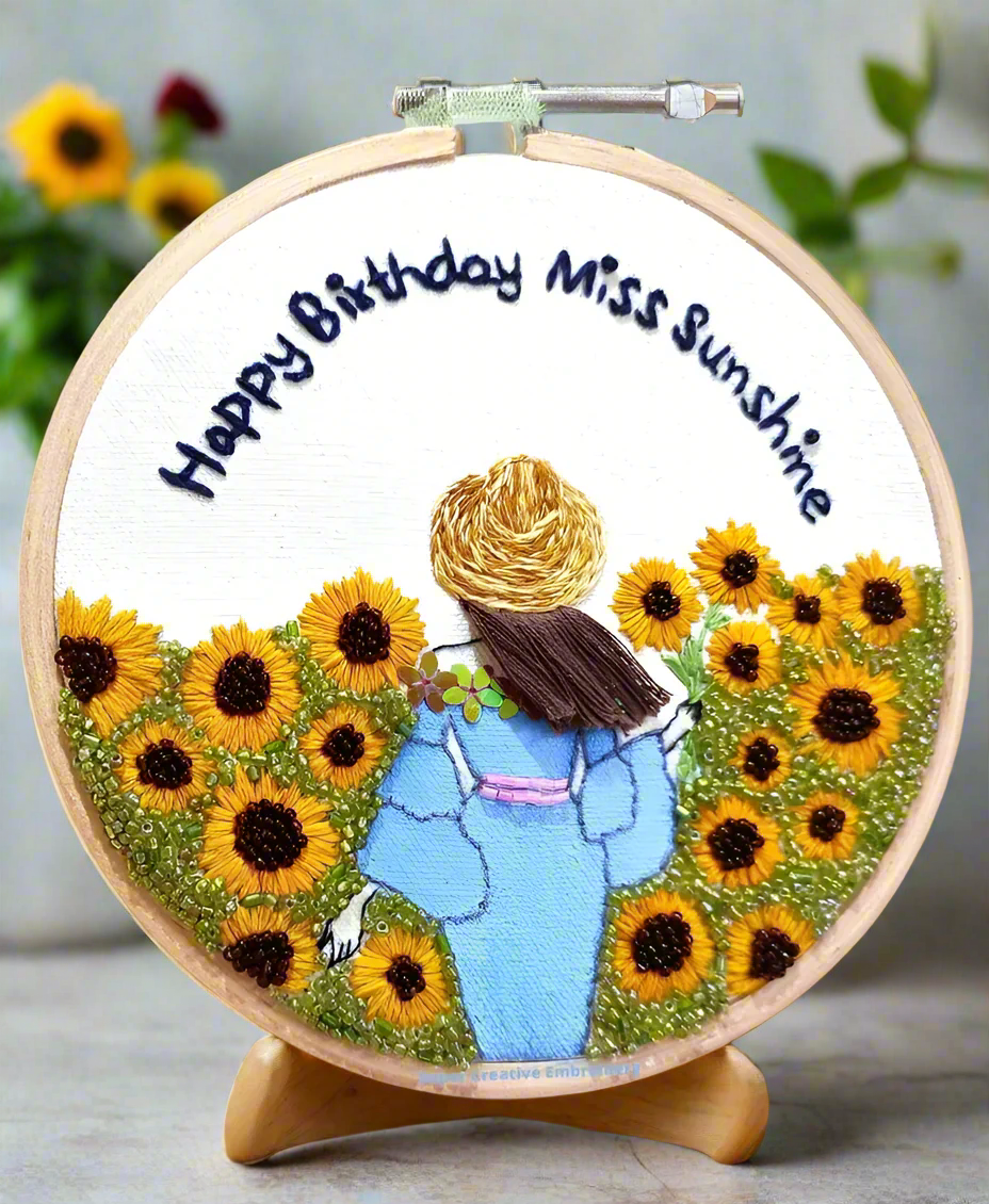 A beaded embroidery artwork with a girl standing among the sunflower field with happy birthday miss sunshine