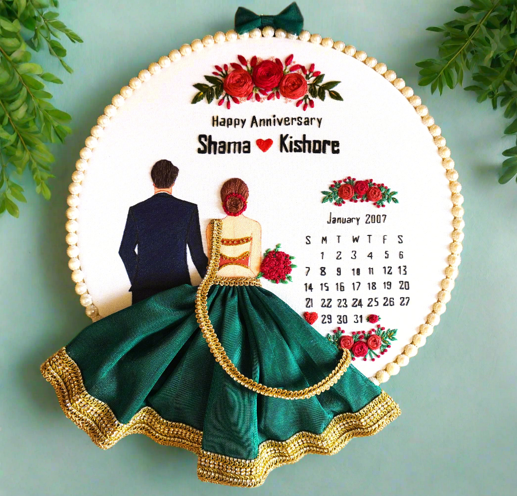 A personalized embroidery hoop gift with a wedding couple design, floral elements, and a calendar background, in green and other colors.